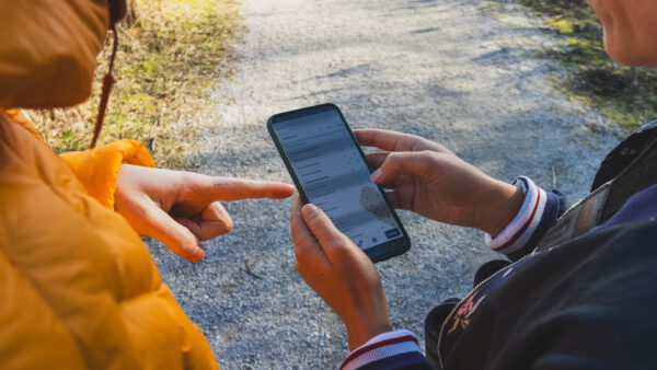 Two birdwatchers are using a mobile phone app to enter data.