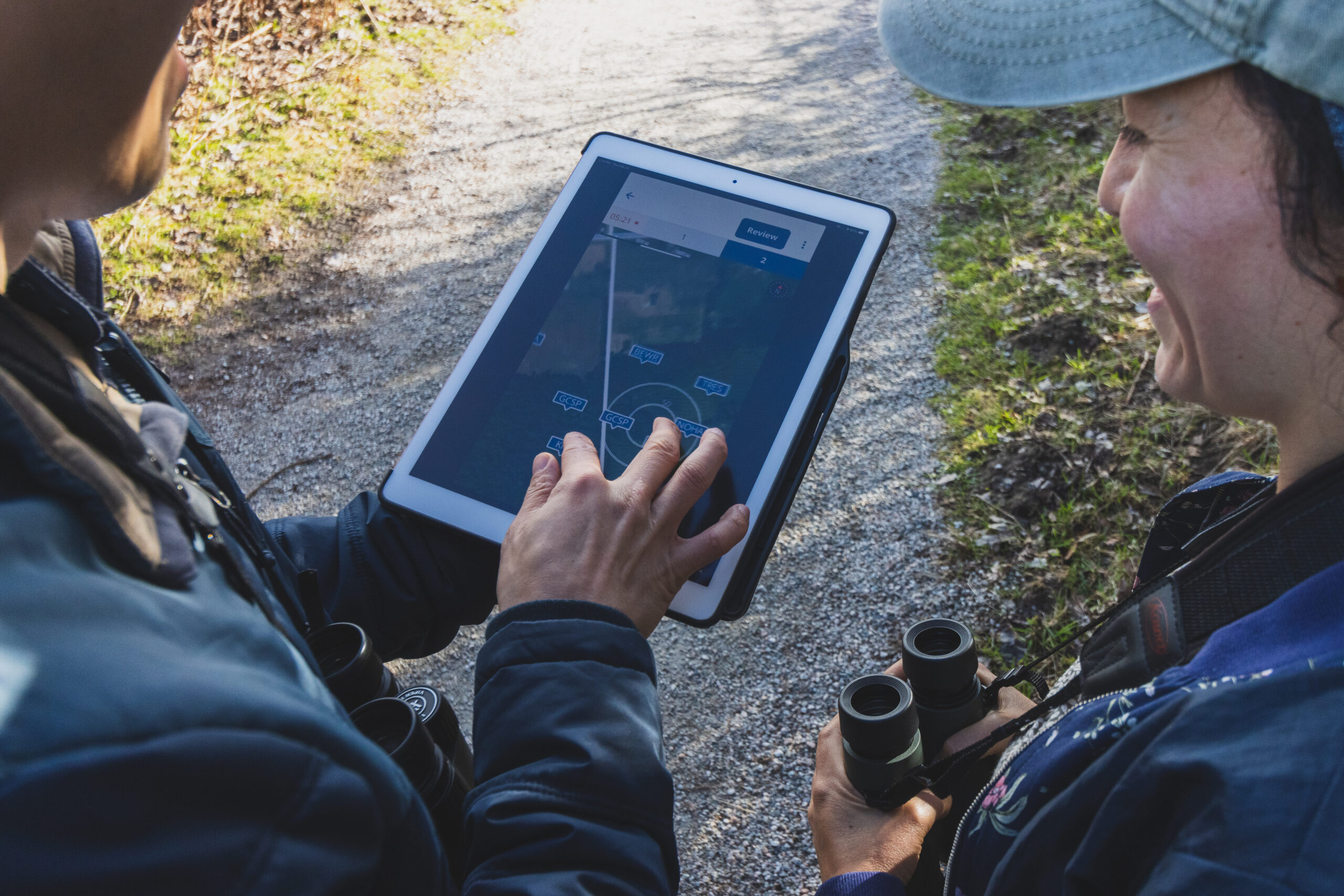 Two birdwatchers are looking at a tablet that is display the NatureCounts point count tool.